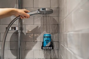 Une main tenant un pommeau de douche, l’eau coulant sur une canette de bière BrewDog Punk IPA, sur laquelle on peut lire l’inscription « GARDEZ MA BIÈRE ».