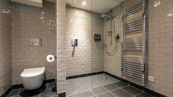 Une salle de bain moderne équipée de toilettes, d’une douche à parois de verre et d’un porte-serviettes.