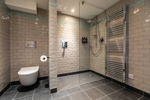 A modern bathroom with a toilet, a glass-enclosed shower, and a towel rack.