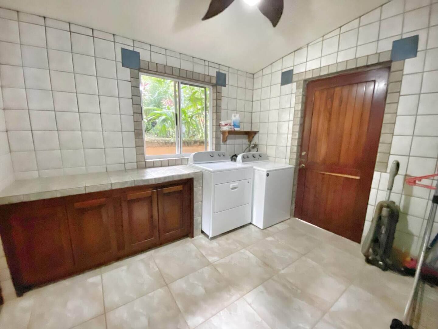 A compact kitchen with a washing machine, a dryer, and a wooden cabinet.