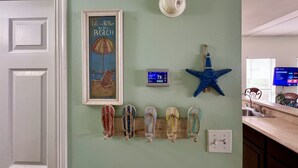 Une pièce décorée sur le thème de la plage, avec un tableau mural, un thermostat, une étoile de mer en guise de décoration et un téléviseur fixé au mur.