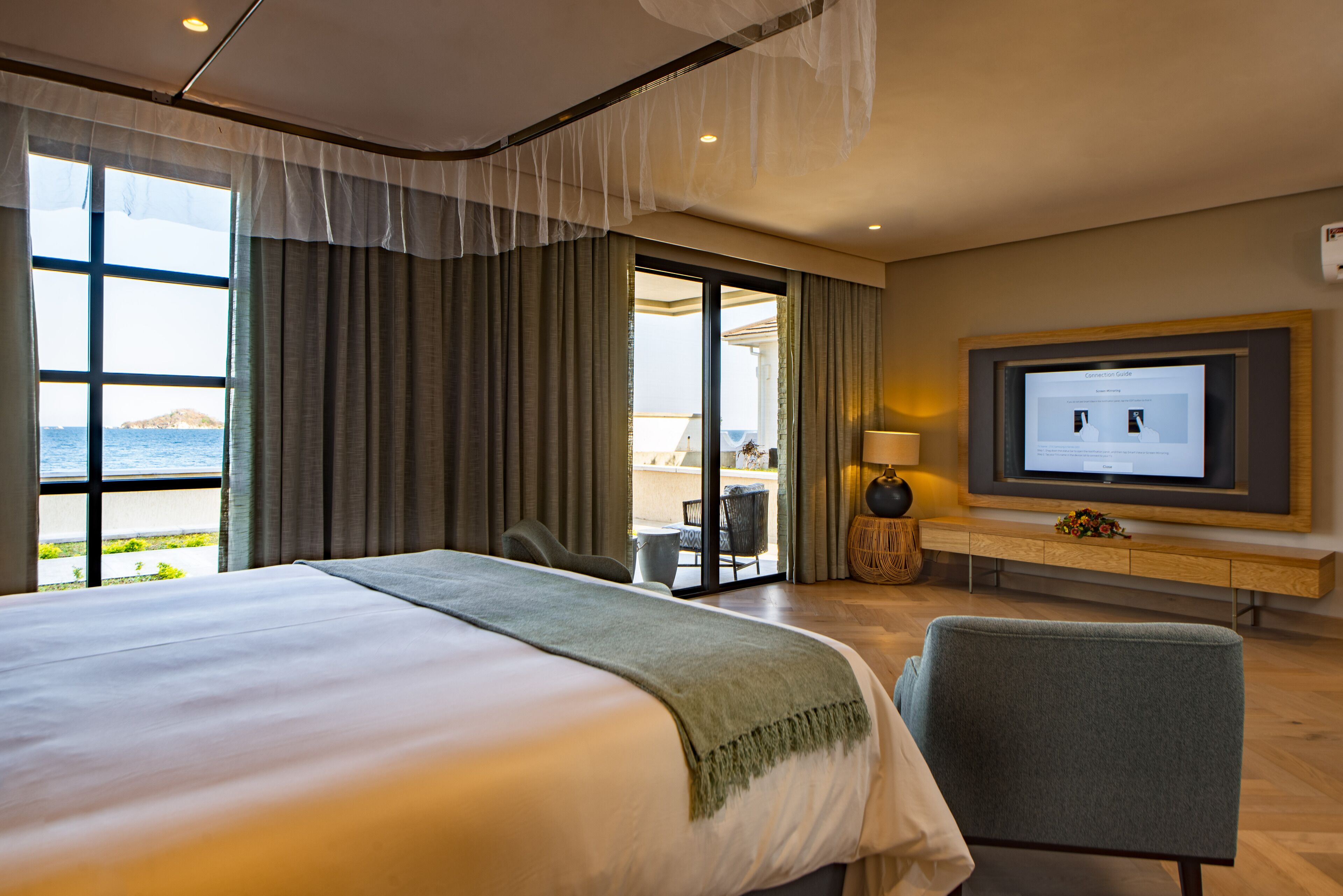 Een hotelkamer met een groot bed, een televisie en uitzicht op zee.