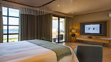 Een hotelkamer met een groot bed, een televisie en uitzicht op zee.