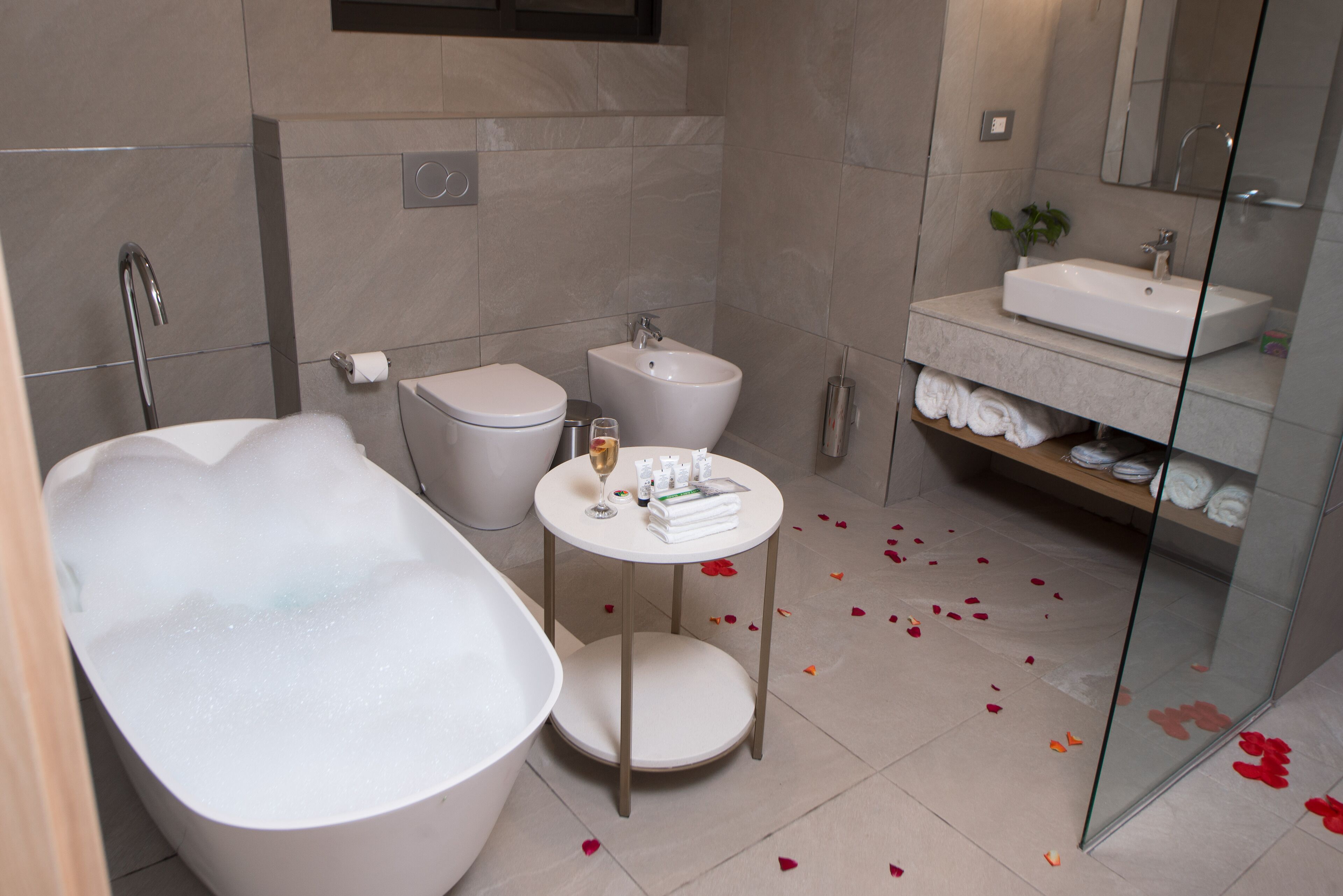 A modern bathroom with a freestanding bathtub, a round vanity with a sink, and a glass-enclosed shower area.