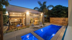 Ein modernes Haus mit großem Garten, zwei Schwimmbecken und einer Essgegend.