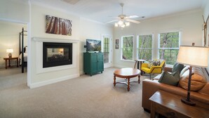 A living room with a fireplace, a television, a green cabinet, a yellow chair, and a brown sofa.