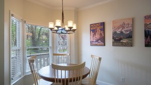 A dining area with a round table, four wooden chairs, a chandelier, and three posters on the wall.