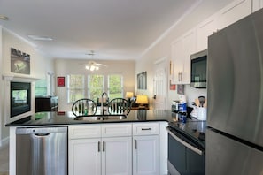 A modern kitchen with a dishwasher, stove, refrigerator, and a ceiling fan.