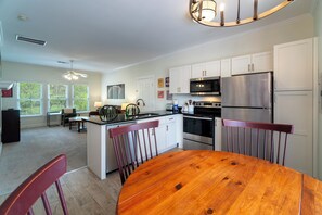 Une cuisine moderne avec des meubles blancs, des appareils en acier inoxydable et une table à manger en bois.