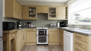 Una cocina con armarios de madera, microondas, tostadora, horno y lavavajillas.