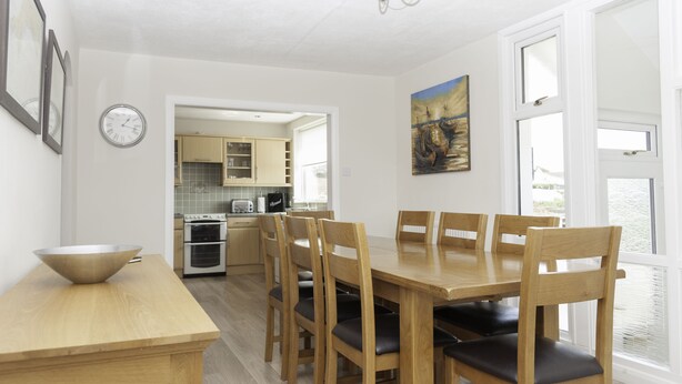 Una cocina moderna con armarios de madera, una mesa de comedor con sillas y un cuadro en la pared.