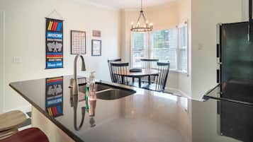 A kitchen with a black refrigerator, a stainless steel sink, and a dining area with a table and chairs.