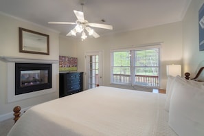 A bedroom with a bed, a fireplace, a ceiling fan, and a window with blinds.