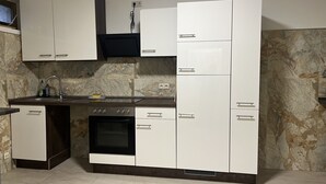 Eine kleine Küche mit weißen Schränken, einem eingebauten Backofen und einem Spülbecken.