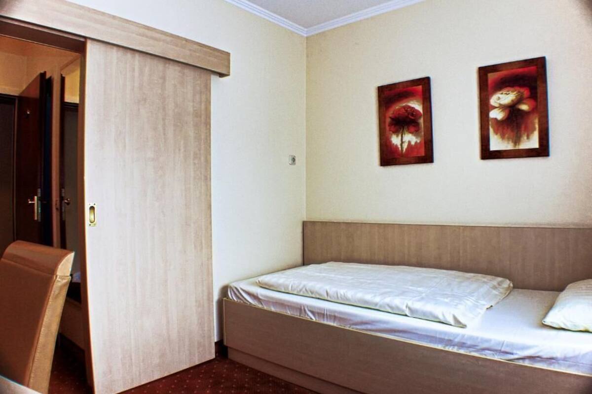 Une pièce comprenant un lit, une chaise et deux tableaux accrochés au mur.