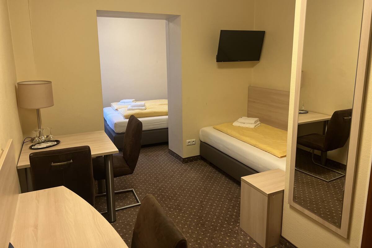 Une chambre d’hôtel avec un lit, un bureau, une chaise, une lampe et un téléviseur.