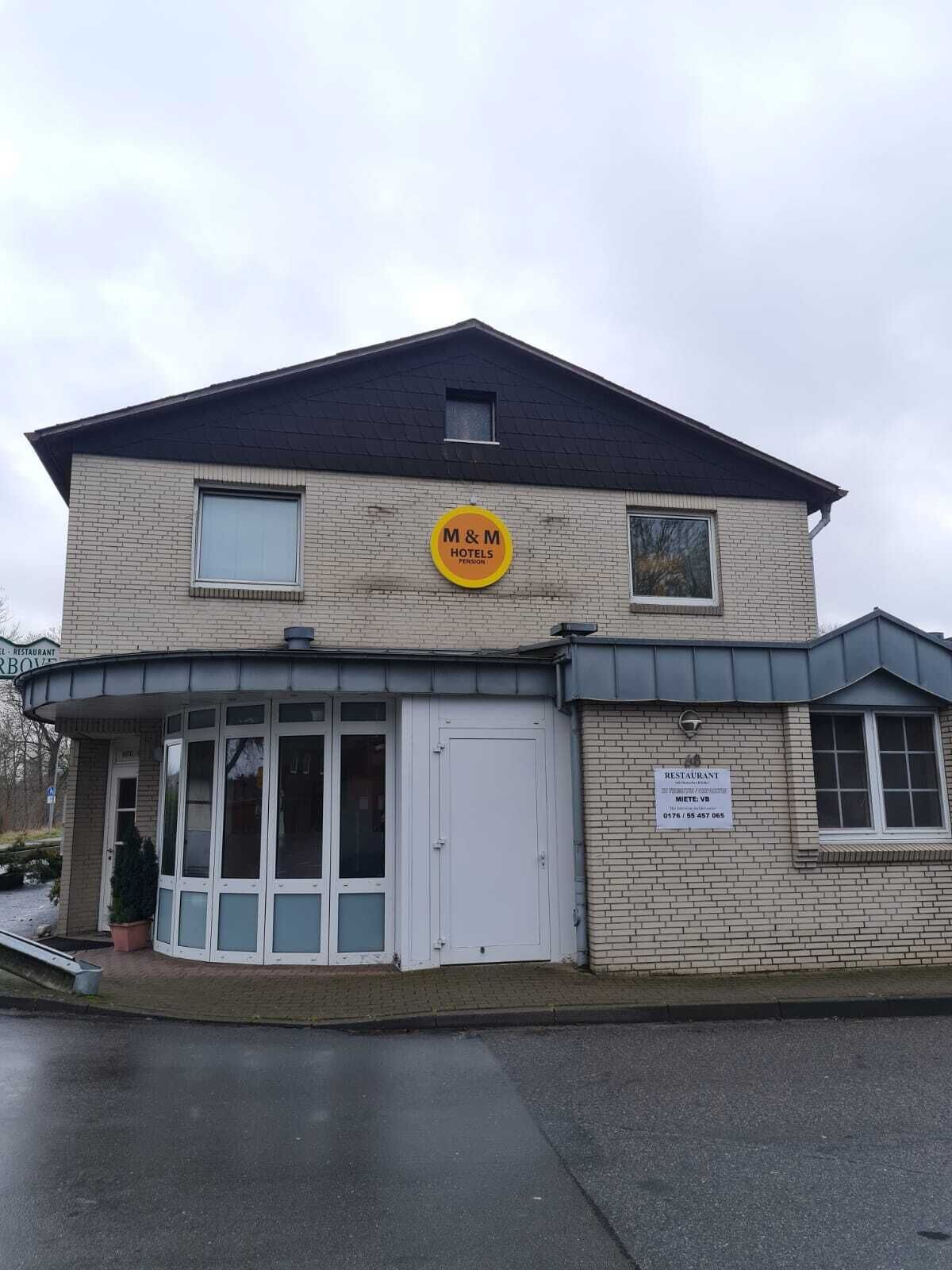 A two-story building with a sign for 'M&M Hotels Pension'.