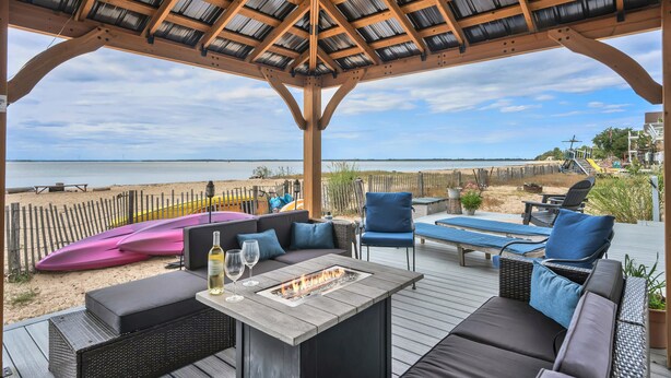 Un espace extérieur aménagé, abrité et doté d’un foyer, de fauteuils confortables et d’une vue sur la plage.