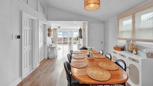 Une cuisine moderne avec une table à manger en bois, des chaises noires et un luminaire suspendu.