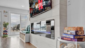 Un intérieur moderne agrémenté d’un grand panneau Netflix, d’un coin salon confortable et d’une table avec des jeux de société.