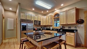 A modern kitchen with wooden cabinets, stainless steel appliances, and a central island with bar stools.