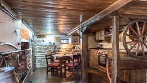 A rustic kitchen with wooden beams, stone walls, and a large wooden wheel. - Villa Viara in Rural Pchelnik (Pchelnik)