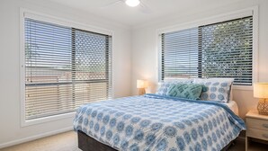 A bedroom with a bed, two bedside tables, and a window with blinds. - The Weekender - spacious townhouse in central location (Evans Head)