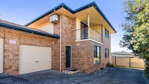 A two-story house with a garage, a balcony, and a brick exterior. - The Weekender - spacious townhouse in central location (Evans Head)