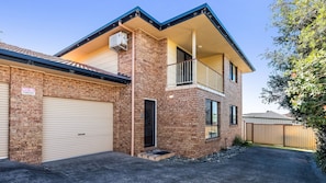 A two-story house with a garage, a balcony, and a brick exterior. - The Weekender - 4-46 Cypress Street (Evans Head)