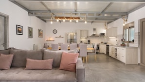 A modern kitchen with a dining area, featuring a sofa, chairs, and a clock on the wall. - Villa Alitocatos (Kissamos)