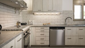A modern kitchen with white cabinetry, a stainless steel dishwasher, and a built-in oven. - Villa Alitocatos (Kissamos)