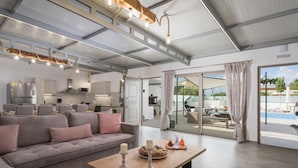 A spacious living area with a sofa, a coffee table, and a view of a swimming pool. - Villa Alitocatos (Kissamos)