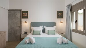 A bedroom with a bed, two bedside tables, a nightstand, a door, and two framed pictures on the wall. - Villa Alitocatos (Kissamos)