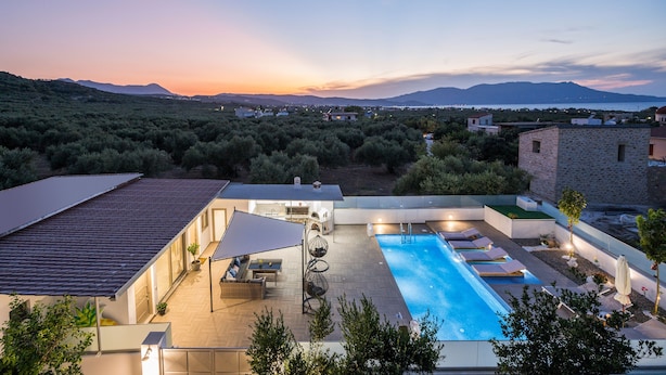 A modern pool area with a view of the sunset and mountains. - Villa Alitocatos (Kissamos)