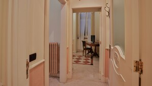 Un pasillo con un radiador, una mesa de comedor con sillas y una puerta con un marco decorativo.