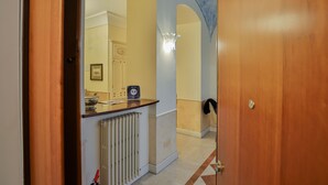 Un pasillo con una puerta de madera, un radiador y un accesorio de iluminación.