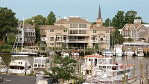Un puerto deportivo con varias embarcaciones amarradas, un edificio de dos pisos con campanario y un edificio más pequeño con la leyenda 'INN'.