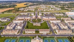 Vista aérea de una zona residencial con casas, un edificio central y canchas de tenis.