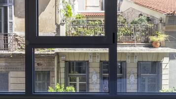 Uma janela com vista para um edifício com varandas e plantas em vasos.