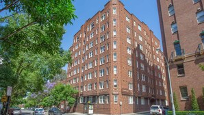A red brick building with multiple windows and a corner entrance. - Stylish Studio Near Kings Cross Train Station (Elizabeth Bay)