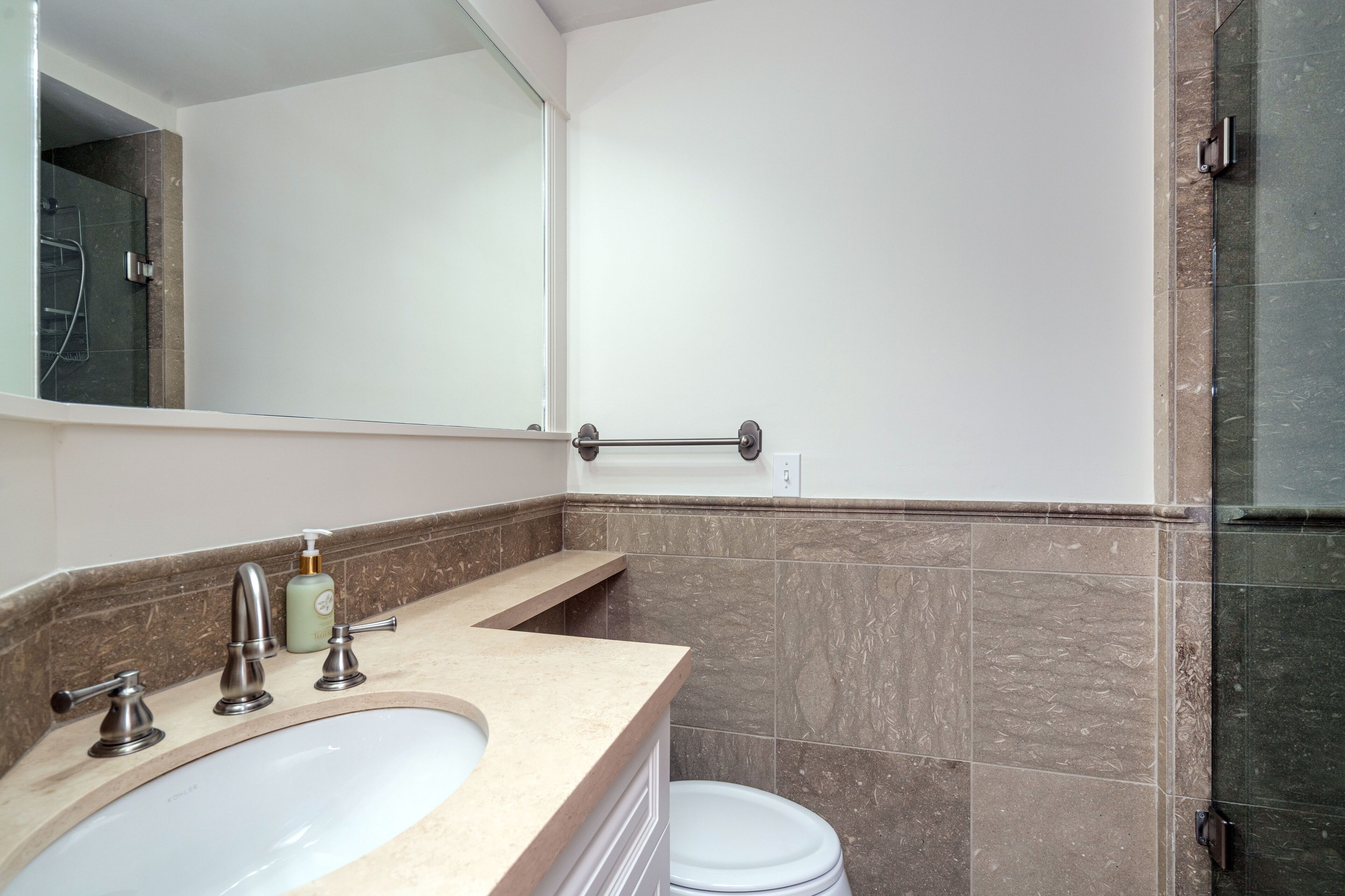 A bathroom with a sink, mirror, and toilet.