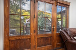 Una puerta corredera de madera con varios paneles de vidrio, que da a un espacio exterior con vista a una montaña y una cabaña de madera.
