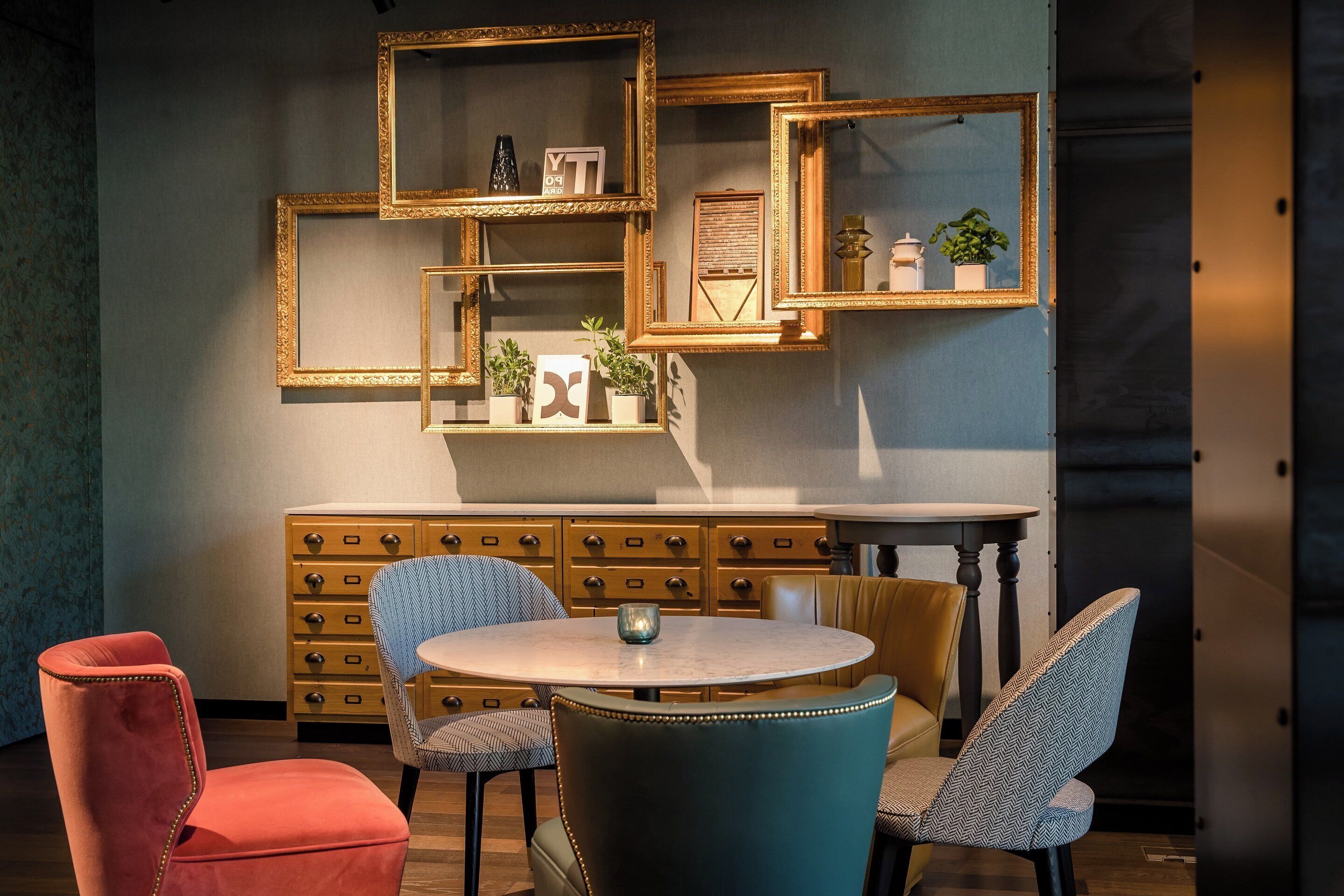 A dining area with a round table, chairs, and a wall-mounted cabinet with drawers.