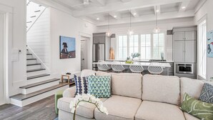 Une cuisine moderne dotée d’un îlot central, de meubles blancs et de luminaires suspendus.