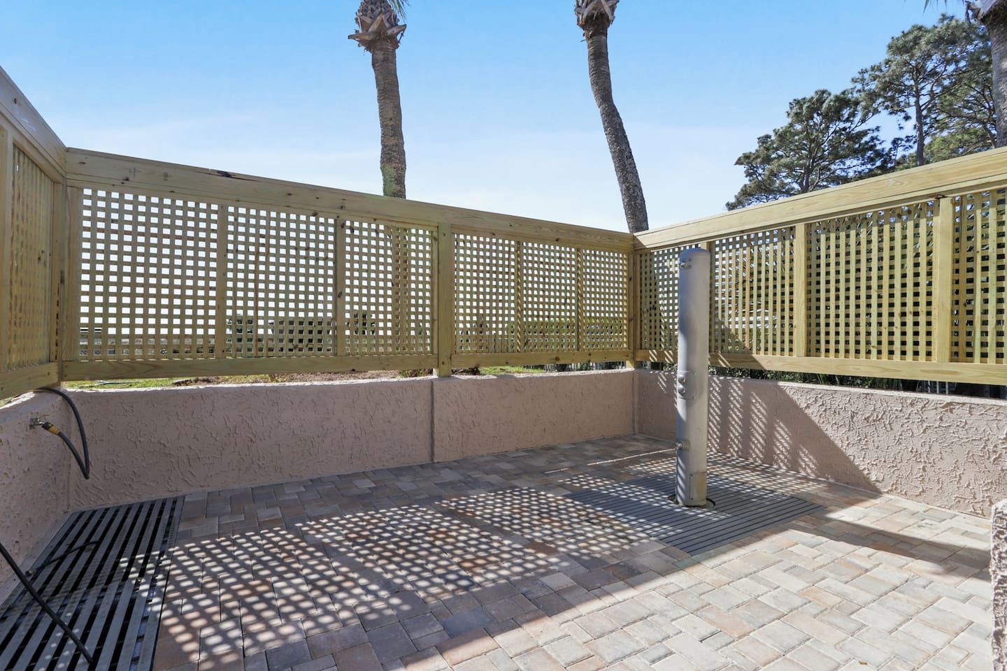 A covered patio area with a wooden fence, a metal bench, and a concrete floor.