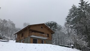 Un chalet en bois doté d’un balcon, entouré d’arbres couverts de neige.