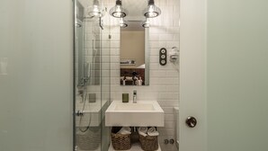 A bathroom with a glass shower enclosure, a white sink, and a mirror above it. - Waou Boutique SOL I (Madrid)