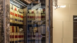 Een kamer met een grote kluis, een houten kist en een oude schrijfmachine op een houten tafel.