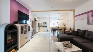 A modern living room with a fireplace, a television, and a dining area with a table and chairs. - 🌸 5-star luxury "Orchidee": Your private spa resort on 85 m² (Arnbruck)