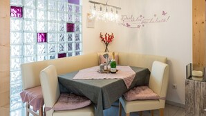 A dining area with a table set for two, a chandelier, and a wall with a decorative phrase. - 🌸 5-star luxury "Orchidee": Your private spa resort on 85 m² (Arnbruck)